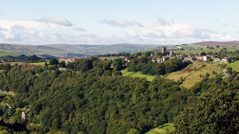 A wide view of the Hardcastle Crags landscape showing wooded valleys, hills and fields